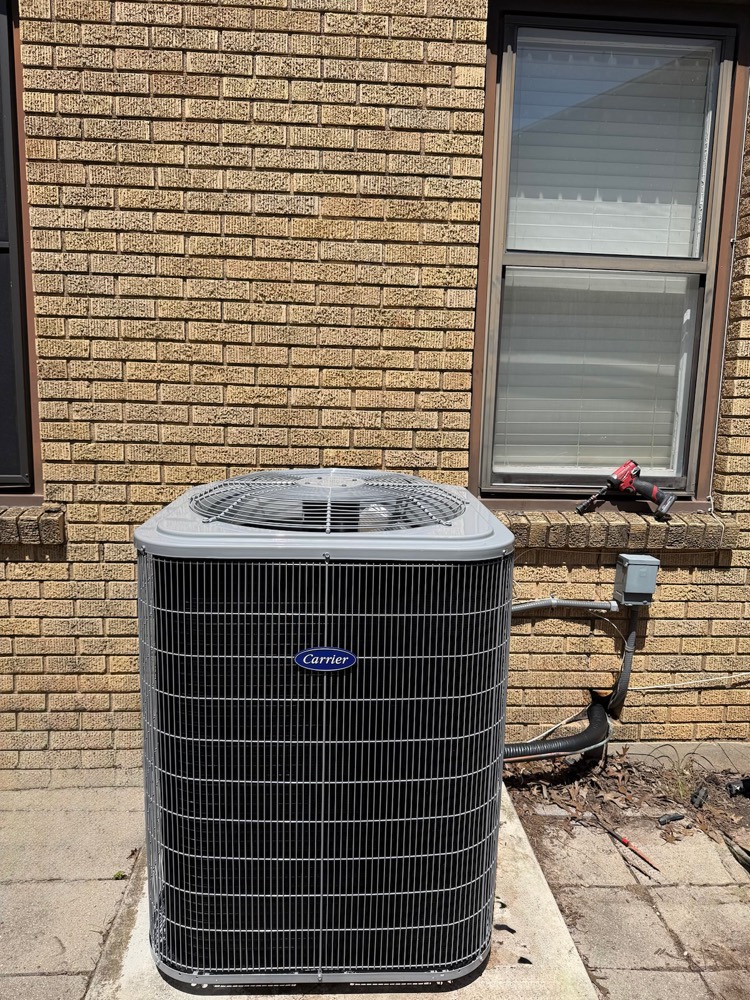 New Carrier outdoor condenser unit beside a brick home